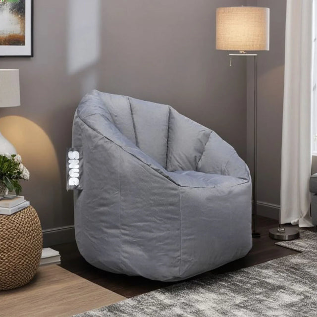 Grey fabric bean bag chair in living room with lamp and textured side table