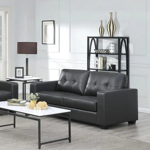 Black leather three-seater sofa with tufted back in modern living room setting