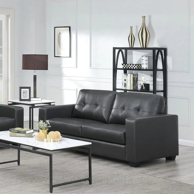 Black leather three-seater sofa with tufted back in modern living room setting