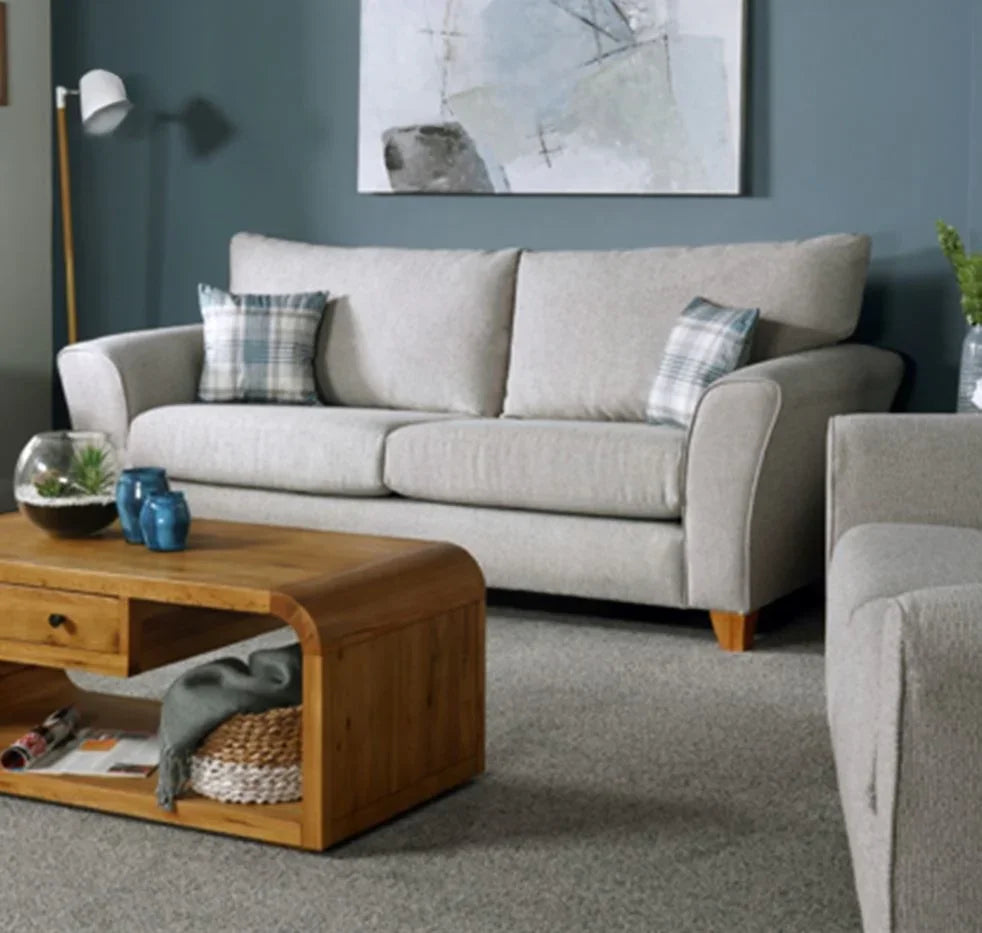 Silver fabric sofa with plaid cushions in living room, wooden coffee table in front