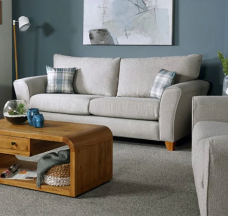 Silver fabric sofa with plaid cushions in living room, wooden coffee table in front