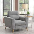 Grey fabric armchair with wooden legs in front of window beside lamp and side table
