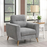Grey fabric armchair with wooden legs in front of window beside lamp and side table