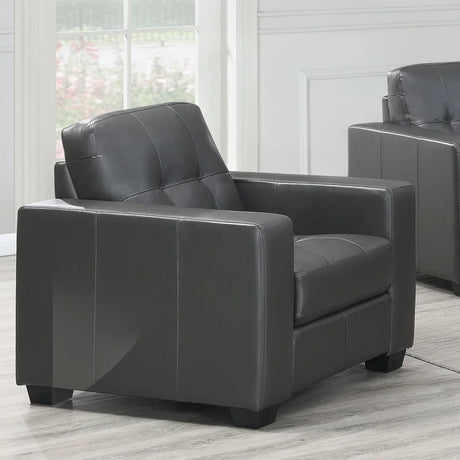 Dark grey leather armchair with square arms and tufted seat in modern living room