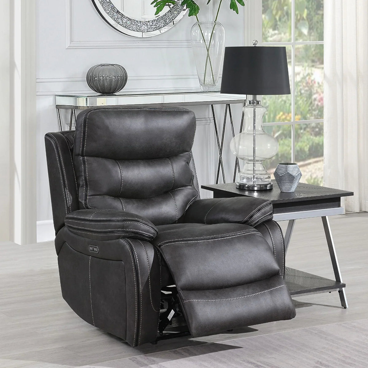 Grey leather recliner chair with padded seat and footrest beside modern lamp table