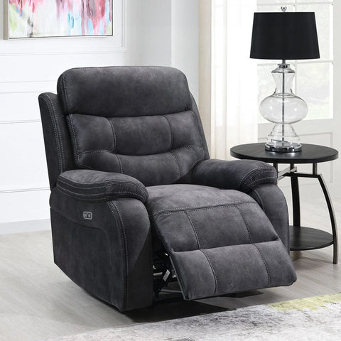 Dark grey reclining armchair with footrest extended beside round black side table and lamp
