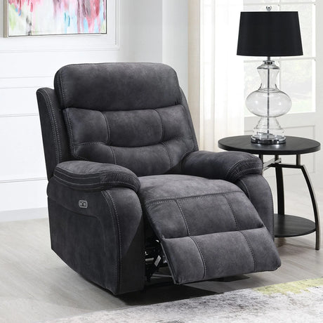 Dark grey reclining armchair with footrest extended beside round black side table and lamp