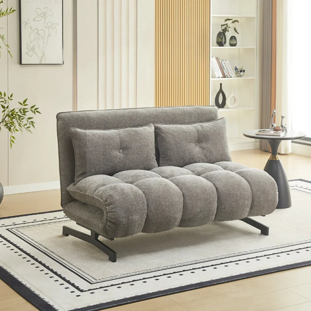 Grey double sofa bed upholstered in soft fabric with tufted cushions in modern living room