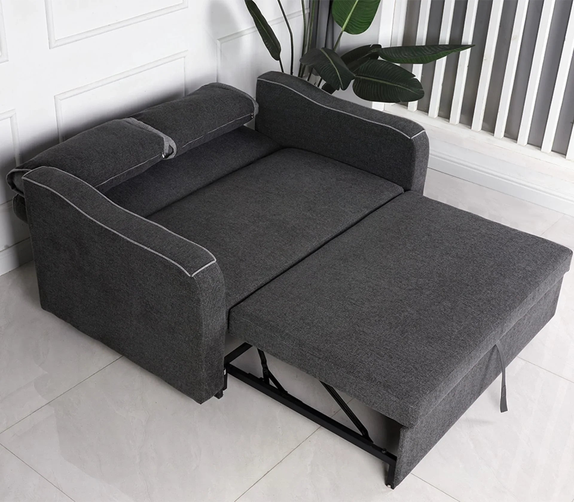 Charcoal fabric sofa bed extended with armrests and headrest in modern room