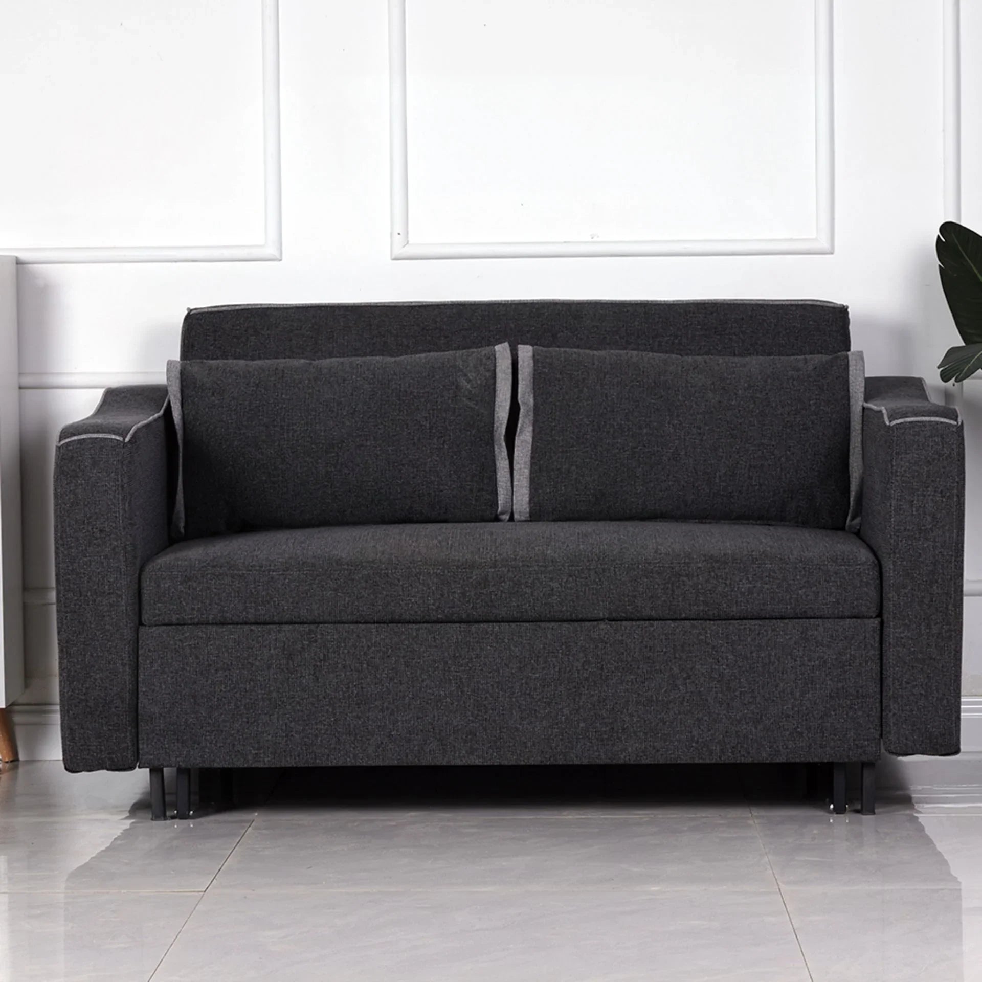 Charcoal fabric sofa bed with two cushions and straight armrests against white panel wall