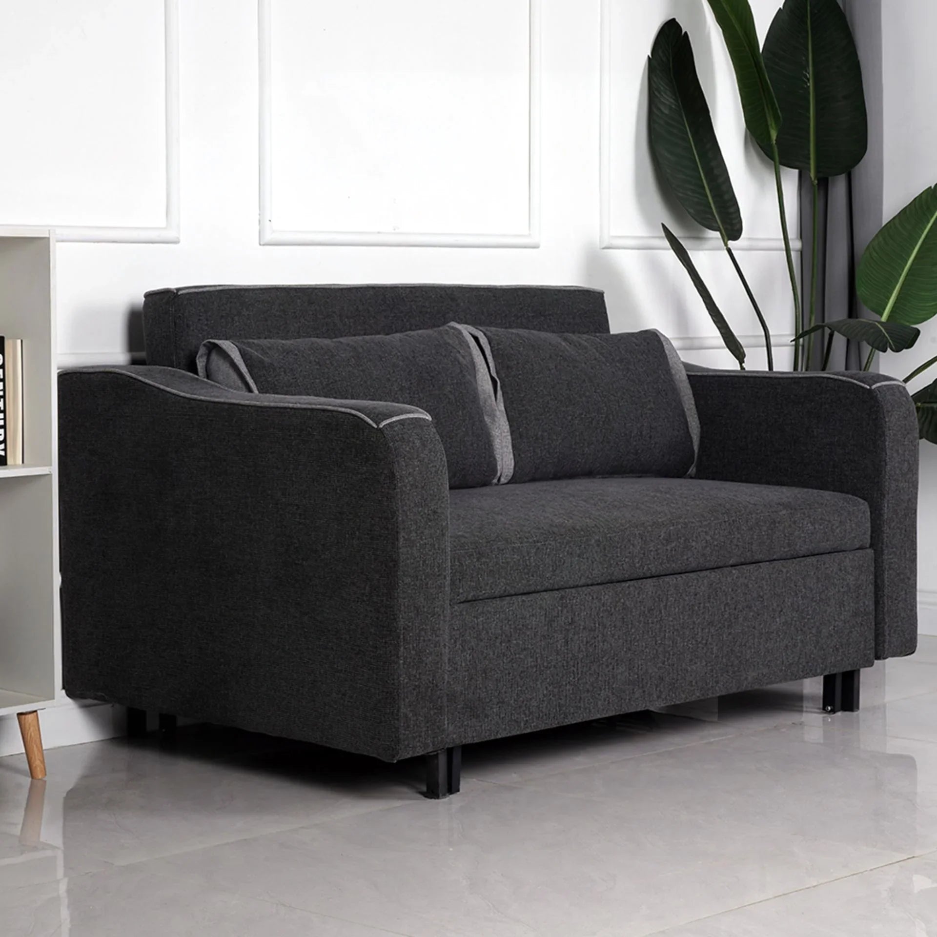 Charcoal fabric sofa bed with two matching back cushions in modern living room setting
