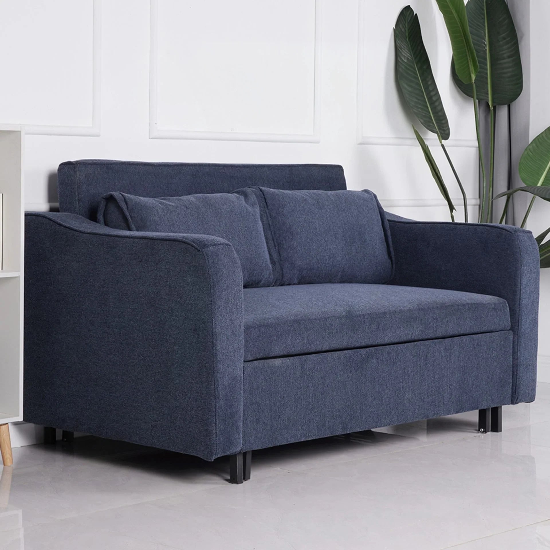 Aspen sofa bed in denim blue fabric with two cushions, modern setting, side view