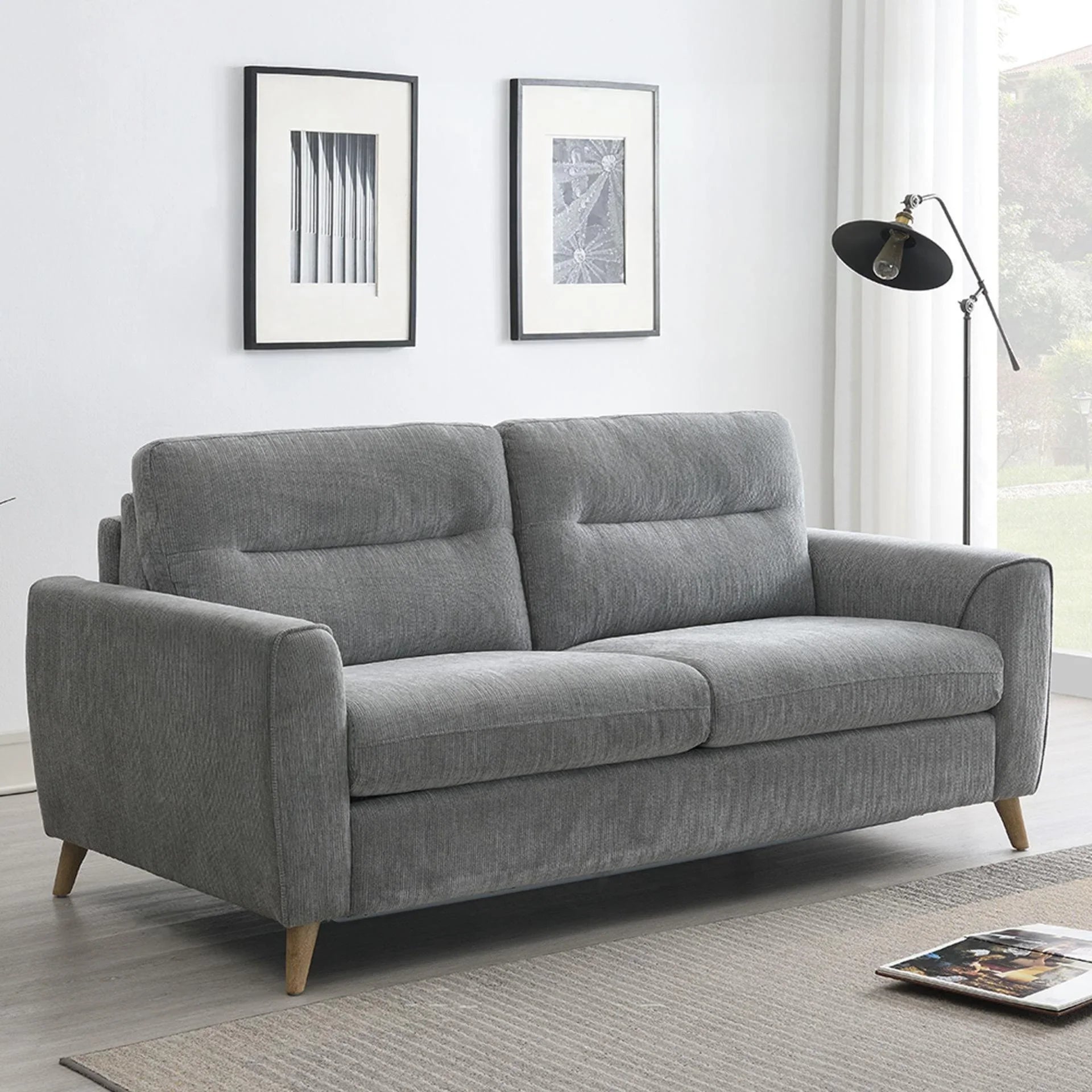 Grey fabric sofabed with wooden legs in a modern living room setting