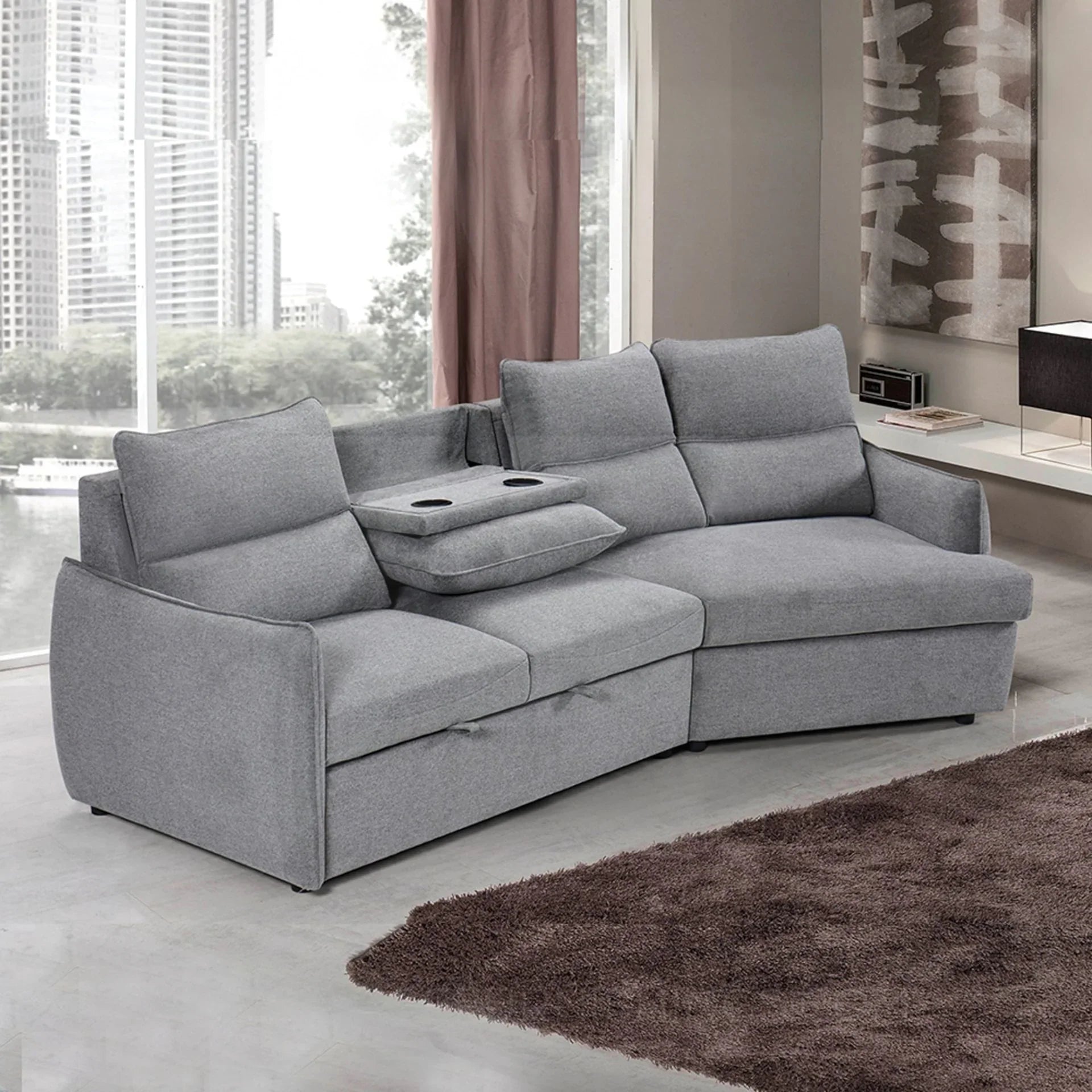 Grey fabric sofa bed with chaise lounge and built-in cup holders in modern living room