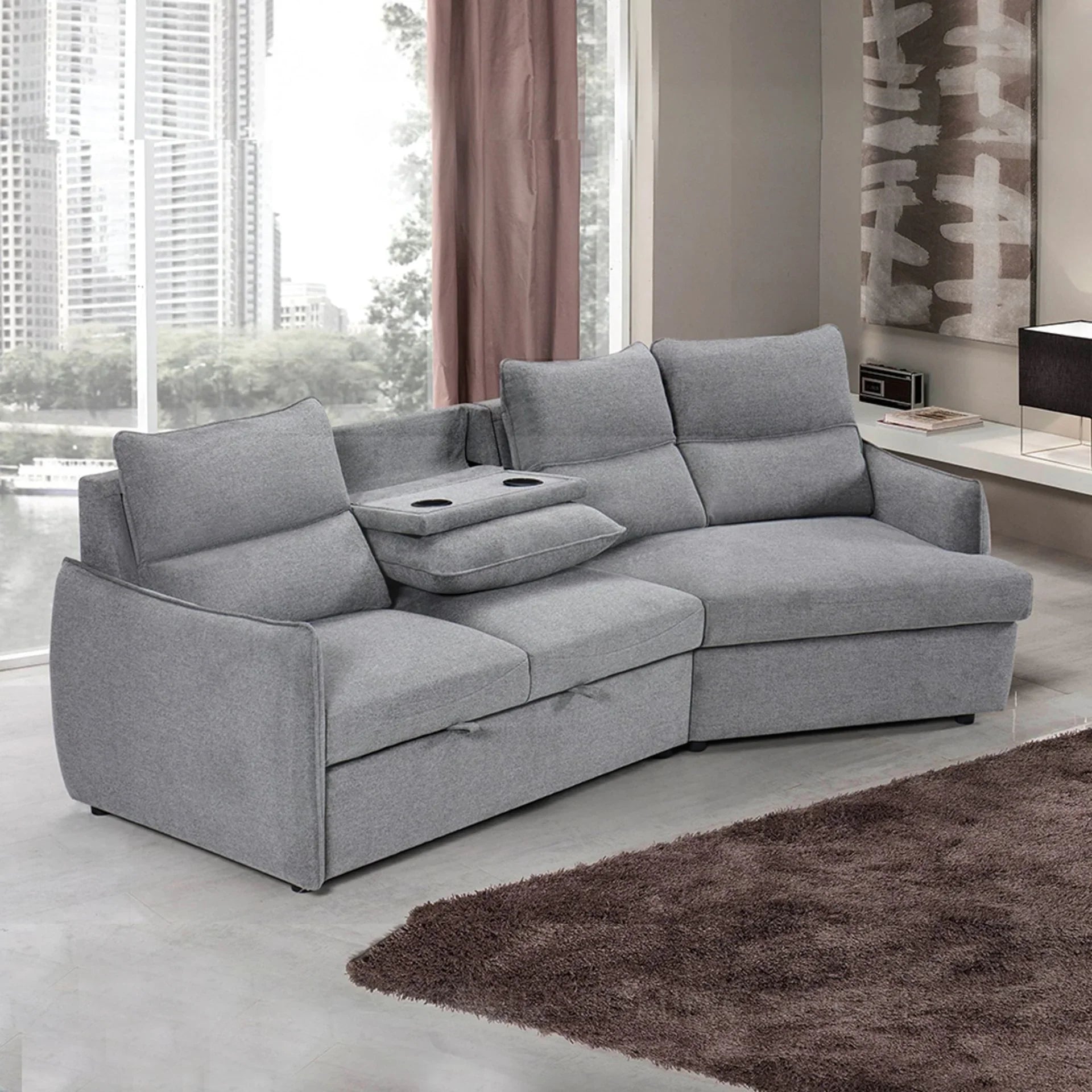 Grey fabric sofa bed with chaise lounge and cup holders in modern living room