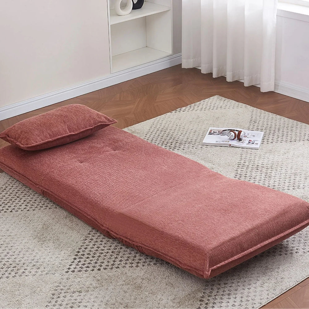 Rust fabric sofa bed with cushion shown flat on a patterned rug in a bright living room
