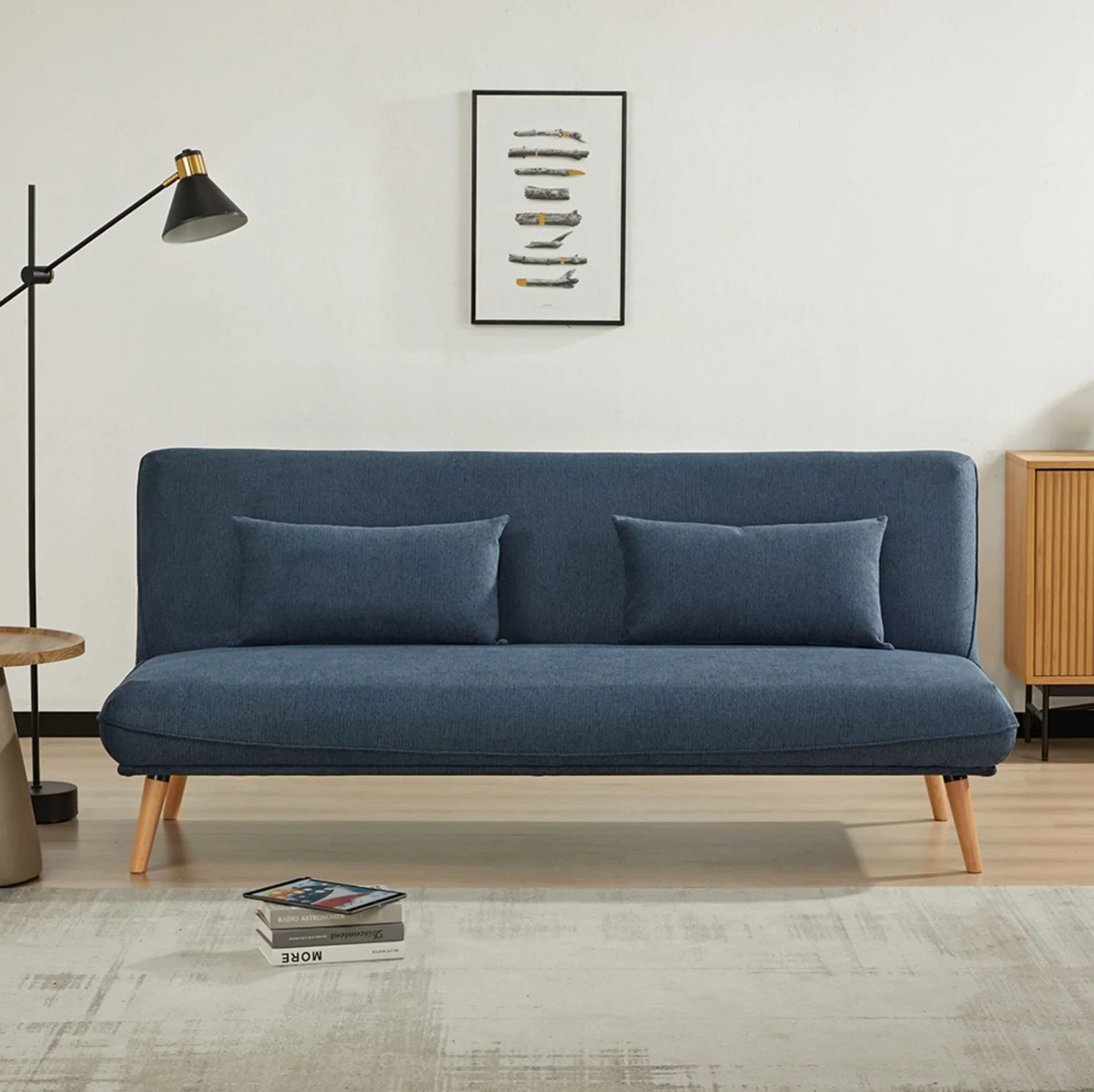 Blue sofa bed with wooden legs and two cushions in modern living room setting
