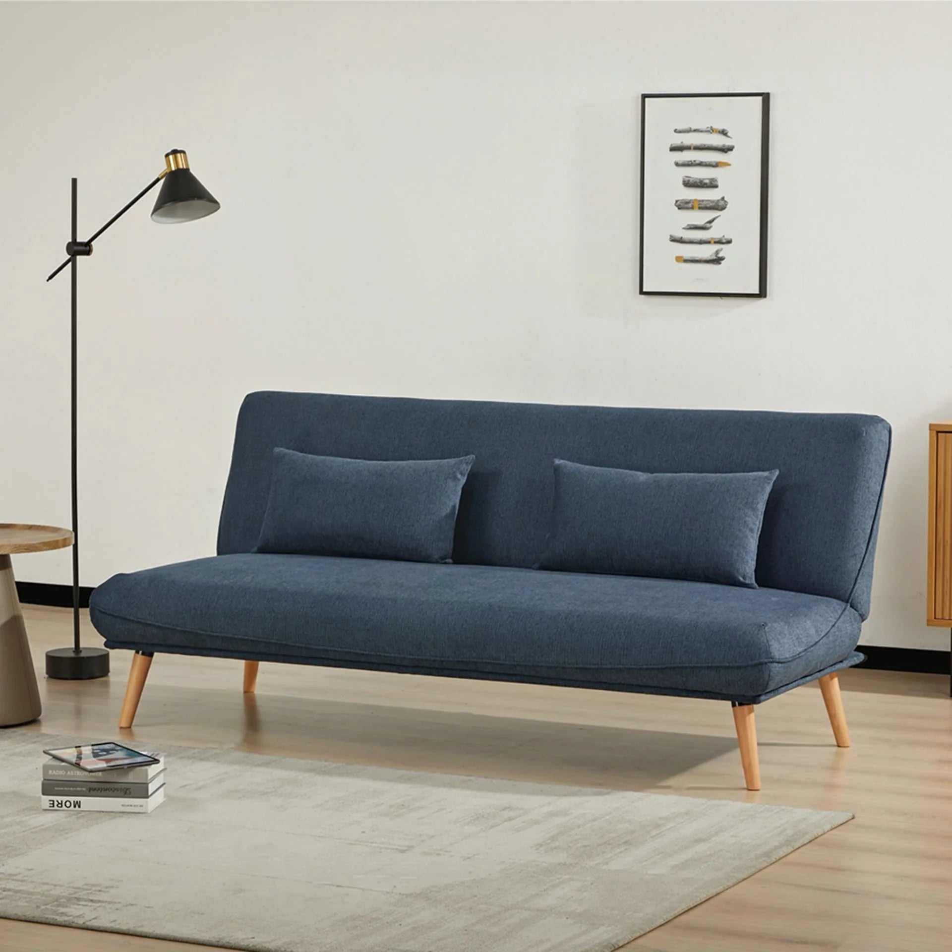 Blue sofa bed with wooden legs and throw pillows in modern living room