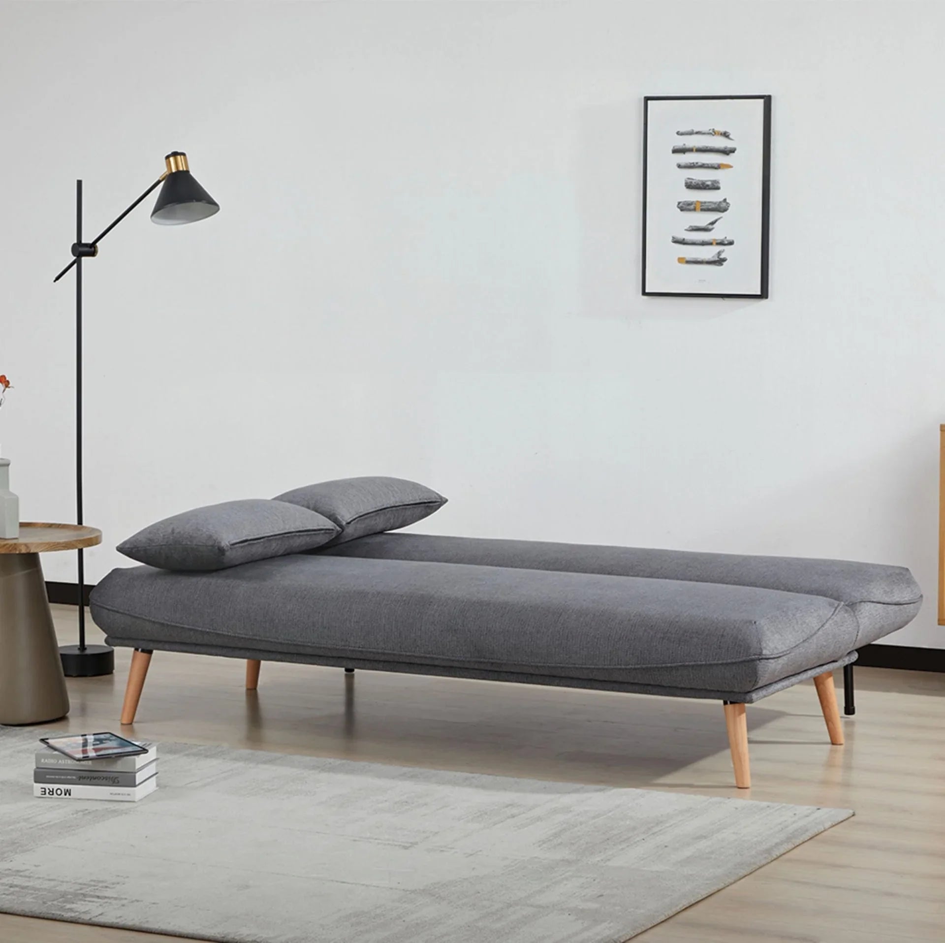 Dark grey sofa bed with wooden legs set up as a bed in modern living room setting