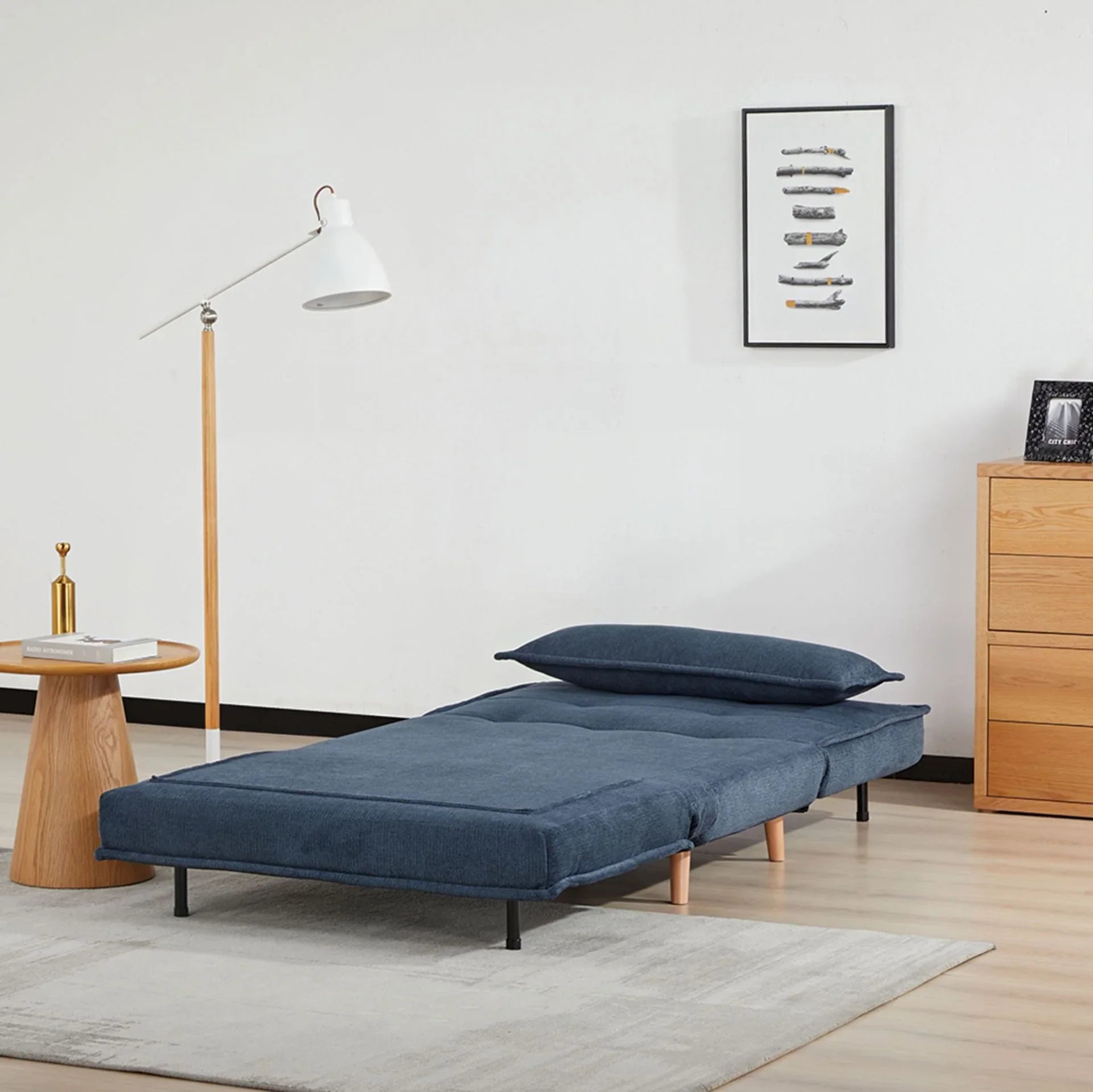 Blue fabric sofa bed extended in modern living room with wooden legs and pillow