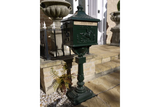 Green cast iron post box with embossed horse design on pedestal by front steps