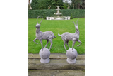 Pair of grey deer garden ornaments on plinths with grass lawn and fountain backdrop