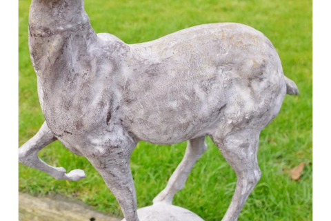 Stone deer garden ornament with weathered texture on grass lawn