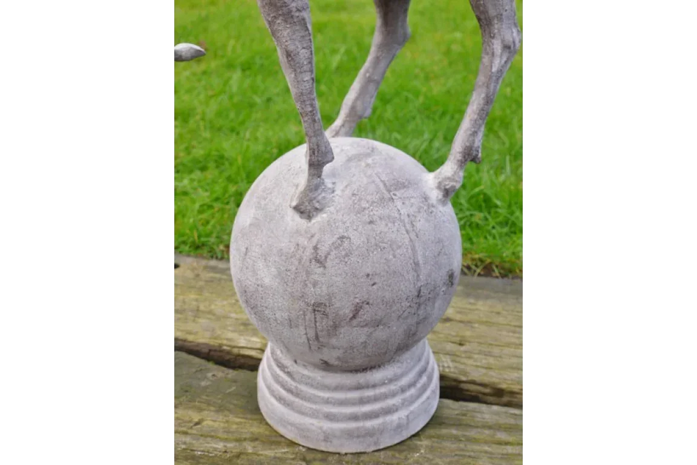 stone garden ornament with animal legs standing on round sphere base, outdoor display