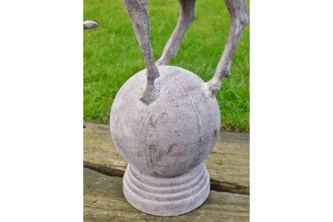 stone garden ornament with animal legs standing on round sphere base, outdoor display