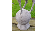 stone garden ornament with animal legs standing on round sphere base, outdoor display
