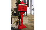 Red cast iron post box with embossed horseman detail on pedestal by stone steps