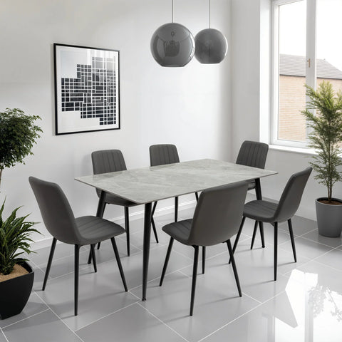 Grey marble dining table set with six modern chairs in a bright tiled dining room