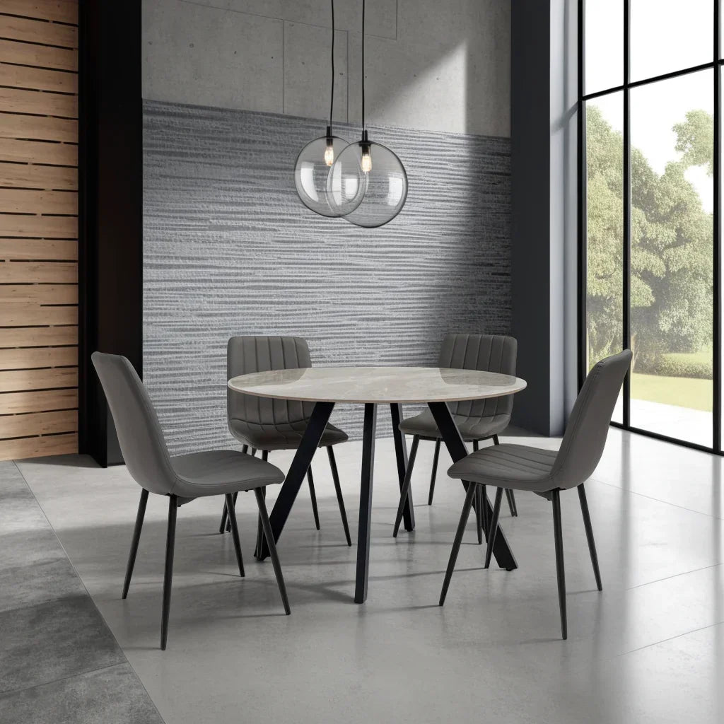 Modern round dining table with marble top and four grey chairs in bright dining room