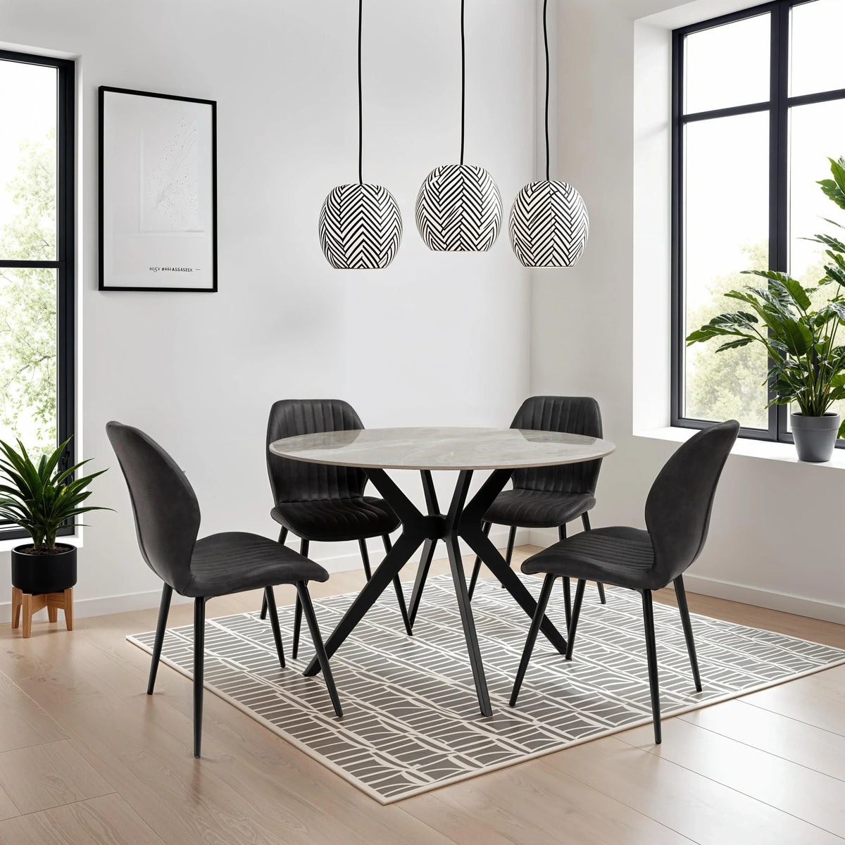 Modern round dining table with black legs and four black velvet chairs in bright dining room