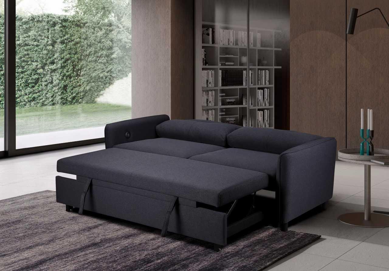 Dark grey fabric sofa bed extended in modern living room with bookshelf and garden view