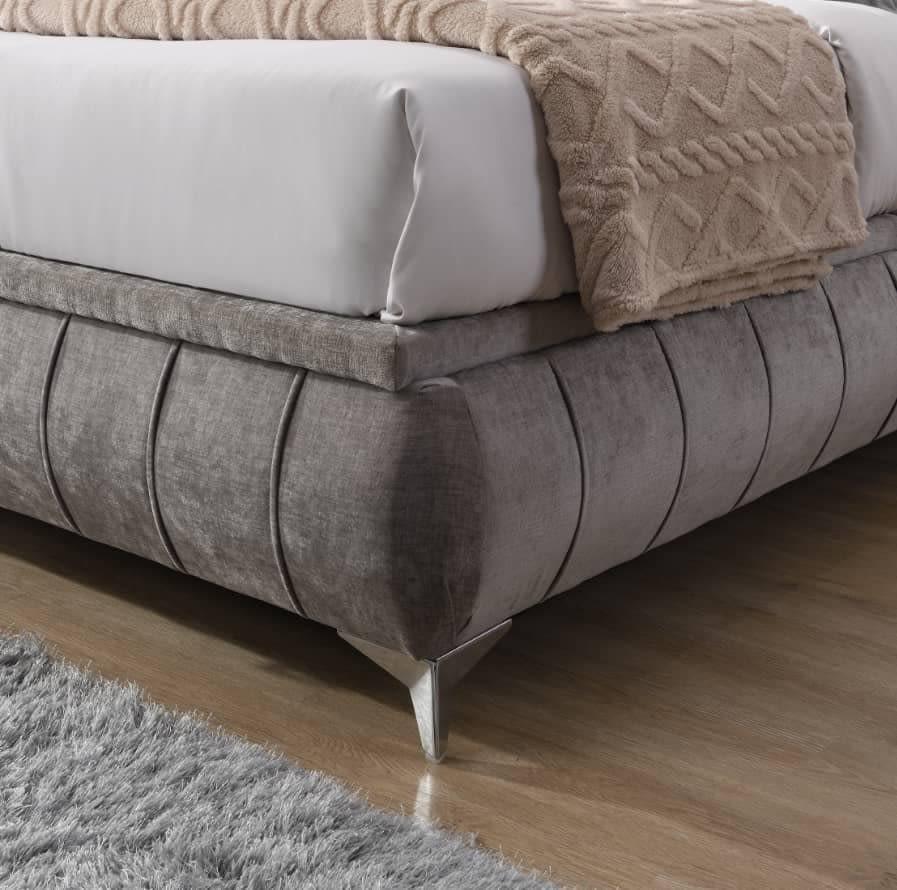 Grey upholstered bed frame with chrome legs and textured blanket on wooden floor