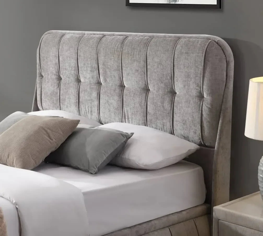 Grey upholstered bed with tufted headboard, white bedding and neutral accent pillows