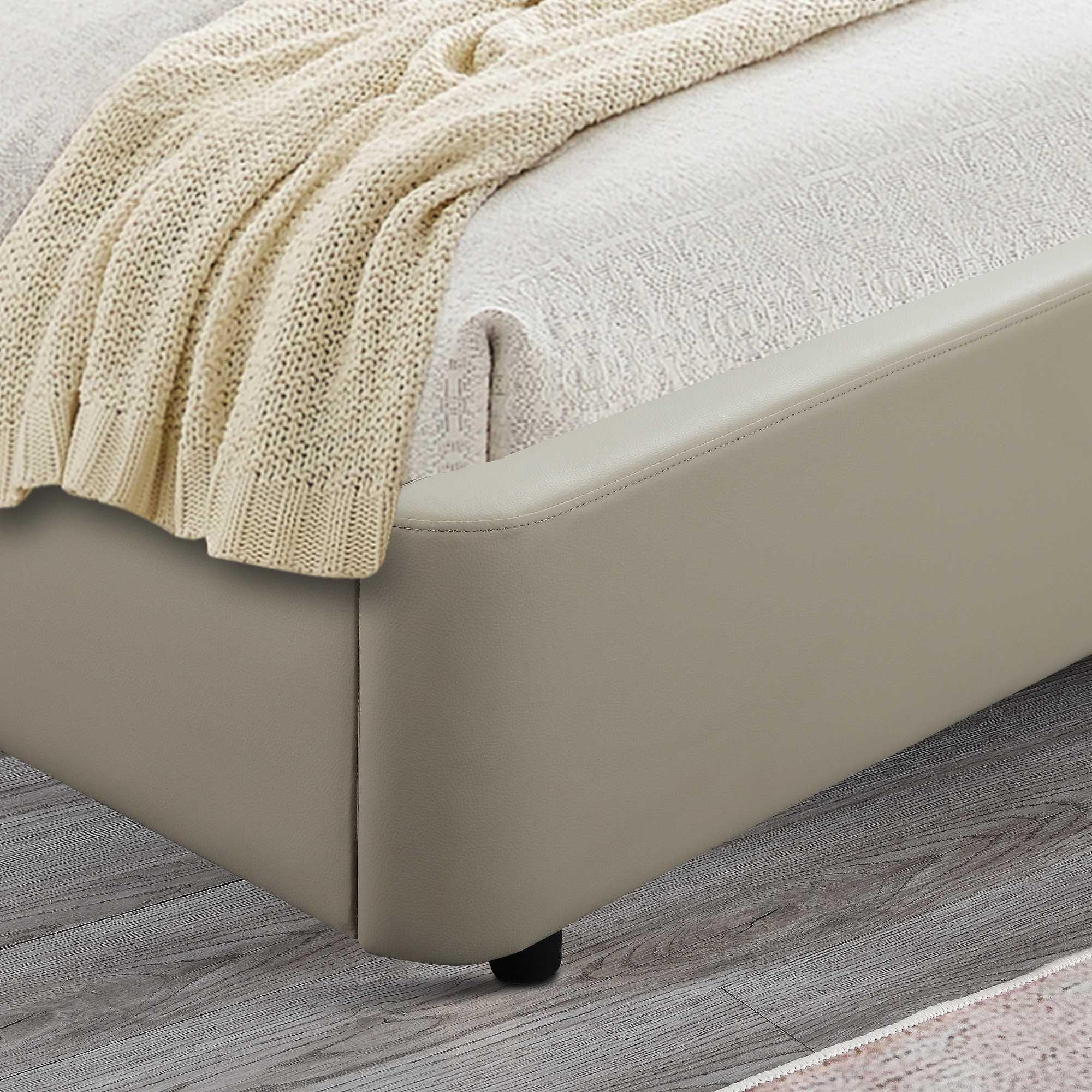 Beige upholstered bed frame with knit throw and textured bedding on wooden floor