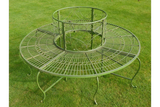 Green metal tree bench with decorative scroll design on garden lawn