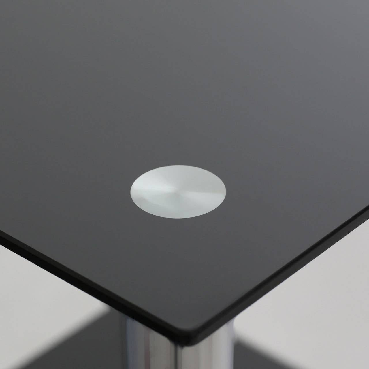 Black glass end table featuring a sleek two-tier design with a circular silver accent on the top surface. The table has a modern aesthetic, suitable for contemporary home decor