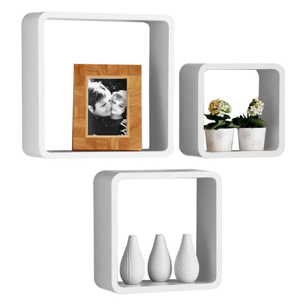 Three white wall cubes of varying sizes arranged in a staggered formation. The largest cube contains three small white vases, the medium cube holds two potted plants, and the smallest cube displays a framed photo. The cubes have a modern, minimalist design suitable for home decor
