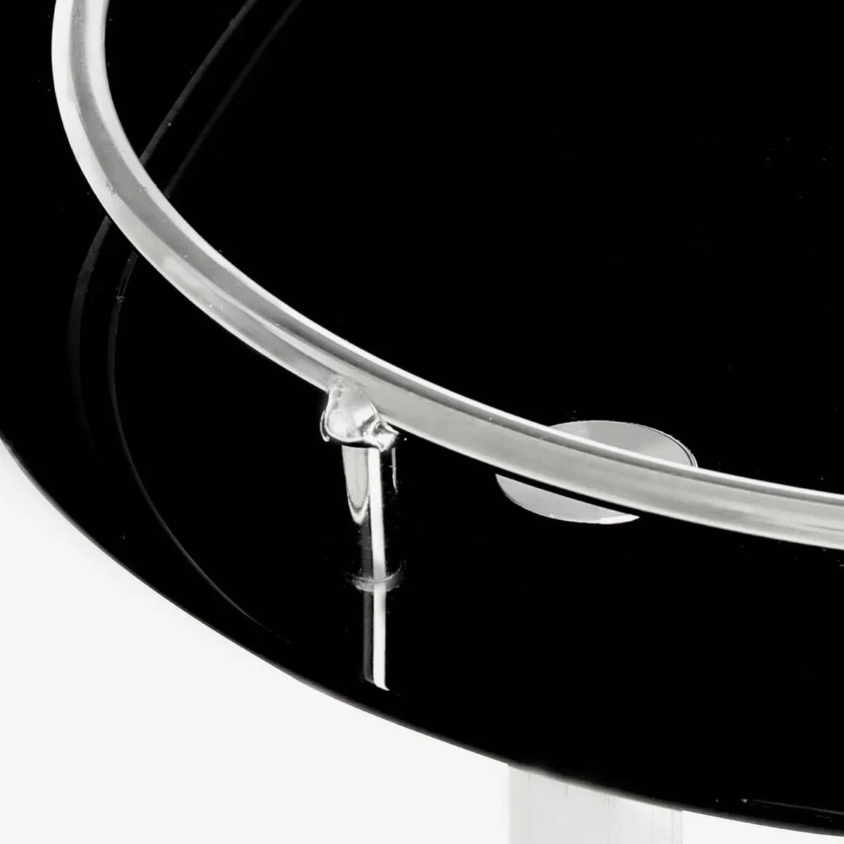 Close-up of black glass side table top with chrome trim and clear support bar