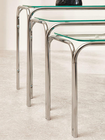 Glass and chrome nesting tables with rounded metal legs on a light floor