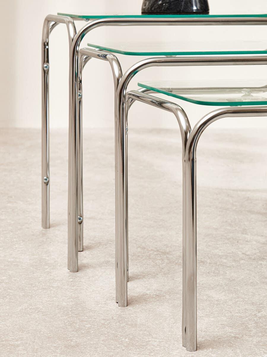 Glass and chrome nesting tables with rounded metal legs on a light floor
