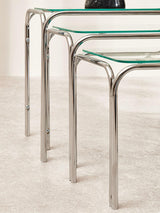 Glass and chrome nesting tables with rounded metal legs on a light floor