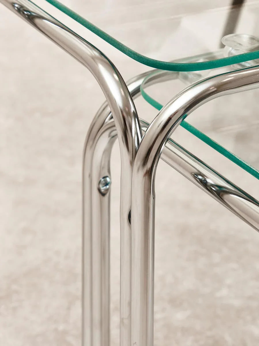 Chrome and glass coffee table corner detail with curved metal frame