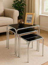Black glass nesting tables with chrome legs in modern living room setting