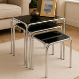 Black glass nesting tables with chrome frames in living room on cream rug
