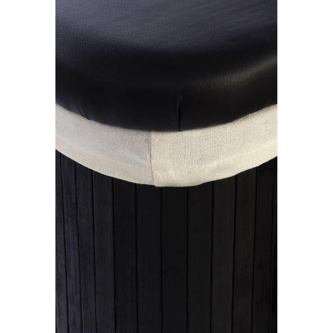 Closeup of black ottoman with cushioned leather top and white fabric trim