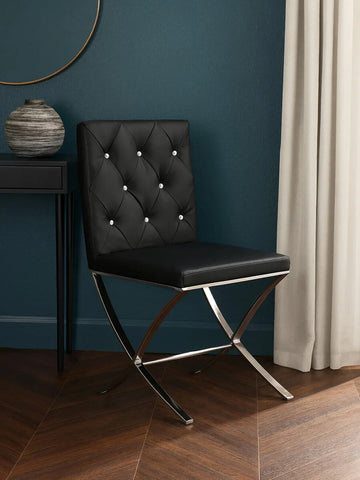 Black leather dining chair with diamond tufted back and chrome legs on wood floor